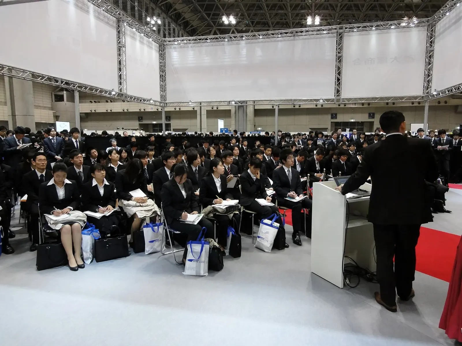 スーツ姿の学生が並んで座る会社説明会の会場