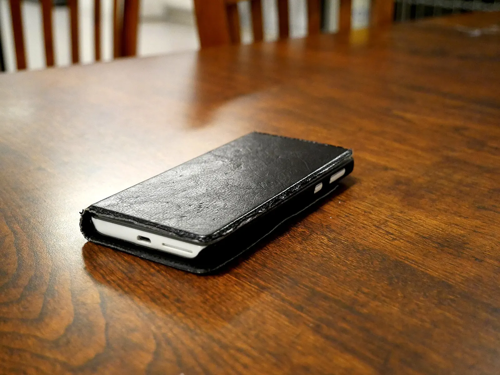 木のテーブルに置いた、手帳型ケースのスマートフォン