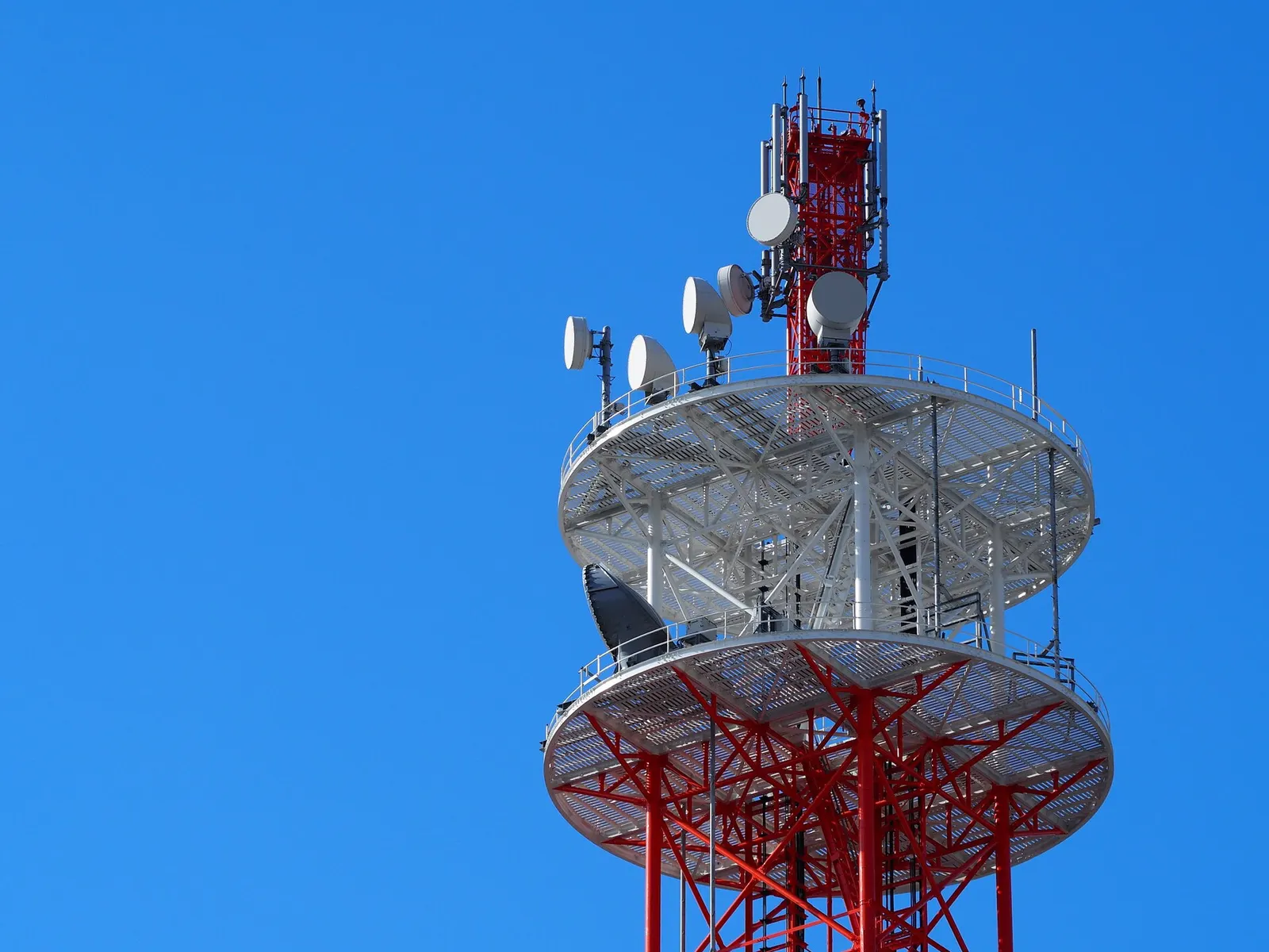 青空の下に立つ、アンテナが並んだ携帯電話の基地局